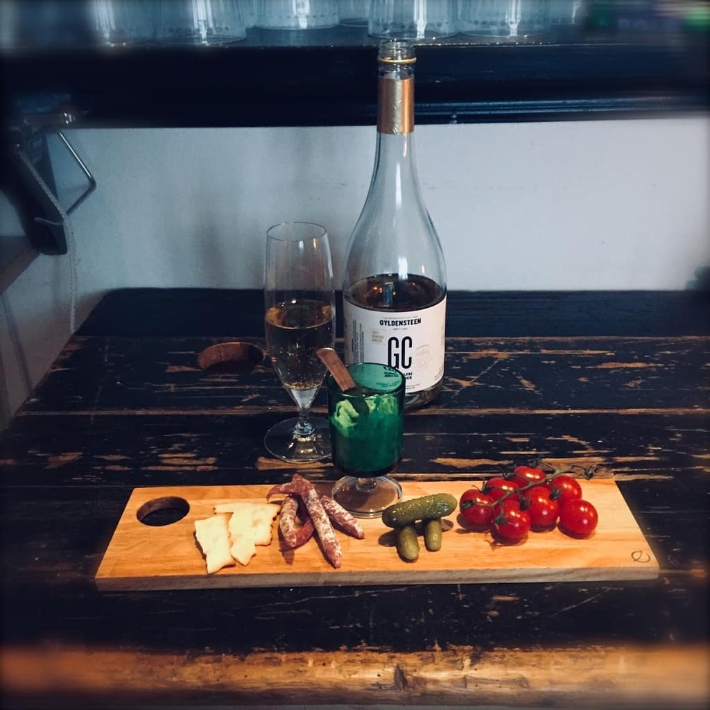 Lille tapasbræt med mad på sort bord og flaske i baggrunden
